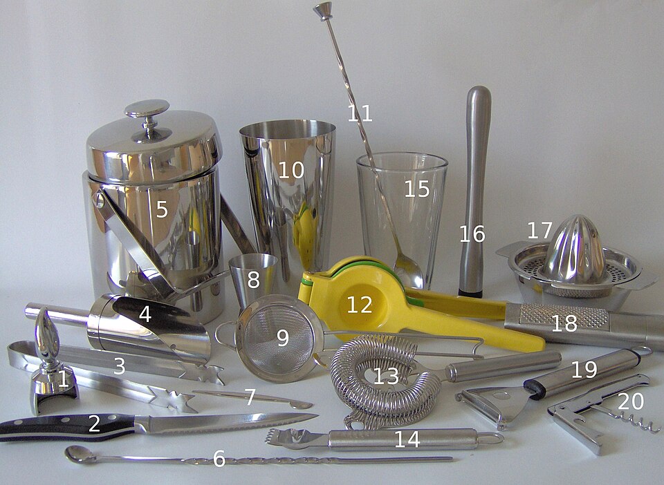 A collection of bar tools including a shaker, strainers, jigger, spoons and citrus presses